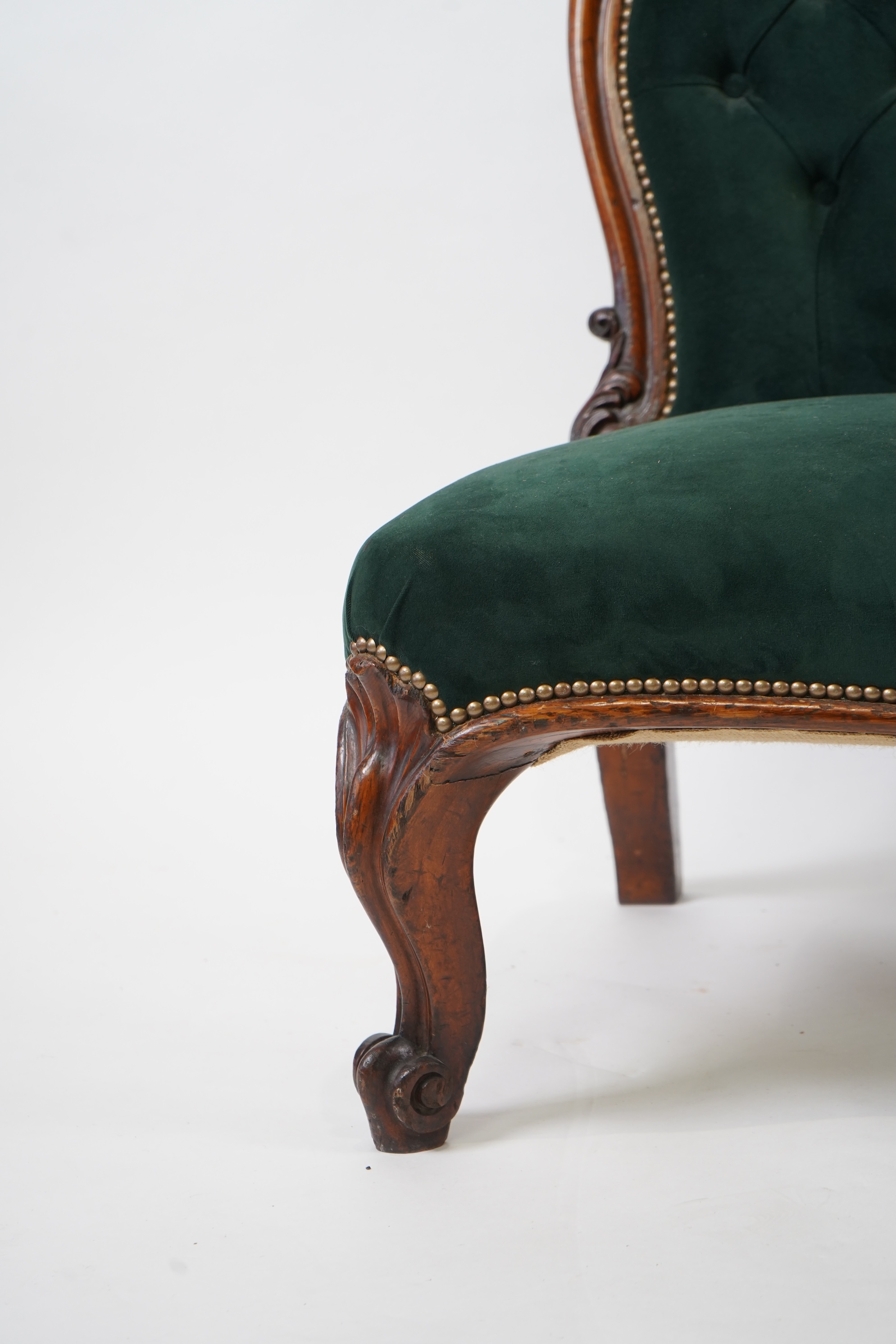 A pair of Victorian carved oak settees, recently re-upholstered in deep buttoned green velvet, the scroll carved crest rails over serpentine seats on cabriole front legs, 160cm wide, 96cm high, Provenance - previously gi